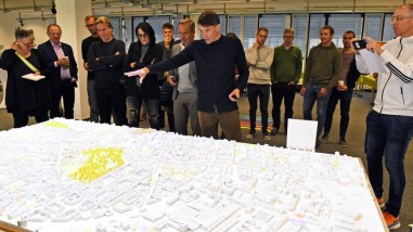 Die umfassende Reichweite REICHWEITE von Litfaßsäulen wurde bei der Auftaktveranstaltung anhand eines dreidimensionalen Modells demonstriert. Personen stehen um ein Architekturmodell.