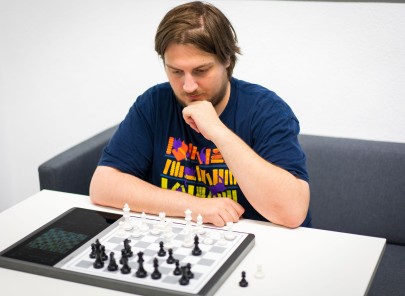 Doktorand Jannis Blüml überlegt seinen nächsten Zug auf dem Schachbrett vor ihm.