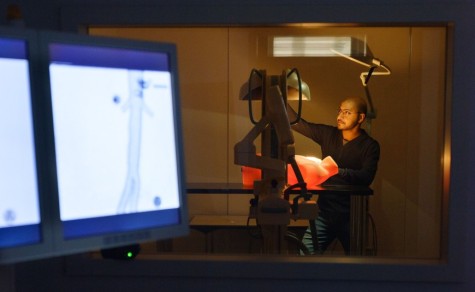 Wissenschaftler bedient medizintechnisches Gerät, im Vordergrund zwei Bildschirme.