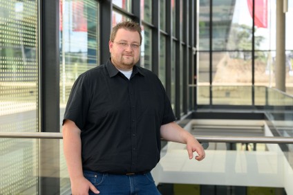 Justus Thies vor unscharfer Fensterfläche, schwarz gekleidet, nur Oberkörper