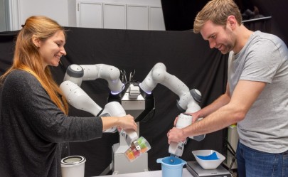 Dorothea Koert und Michael Lutter zeigen dem Roboter eine Küchenaufgabe, sodass er diese nach der Demonstration selbstständig durchführen kann.