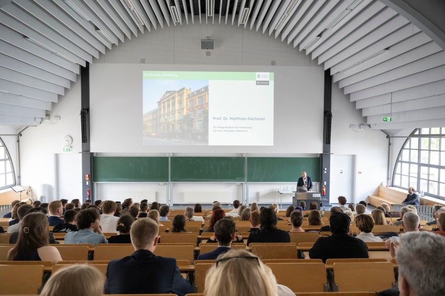 Hörsaal Maschinenhaus von der letzten Sitzbank aus Richtung Tafel fotografiert mit Publikum.